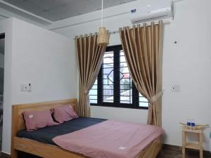 1 dormitorio con 1 cama y una ventana con cortinas en Xuka Homestay, en Hue