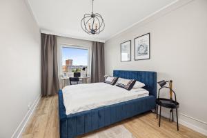 a bedroom with a blue bed and a window at Marina Primore - Hampton Apartments in Gdańsk