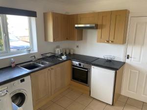 a kitchen with a sink and a dishwasher at Fern Cottage in Thorpe le Soken