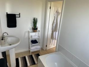 a white bathroom with a sink and a shower at Fern Cottage in Thorpe le Soken