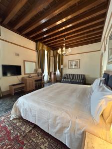 a bedroom with a large white bed and a desk at Foscari Palace in Venice