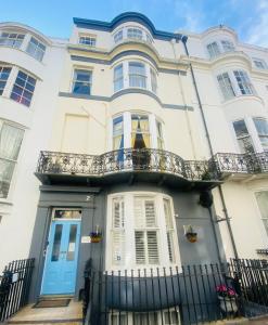 a white house with a blue door and a balcony at Blue Sky Guest House in Brighton & Hove