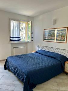 a bedroom with a blue bed and two windows at Appartamento Borgomarina in Cervia