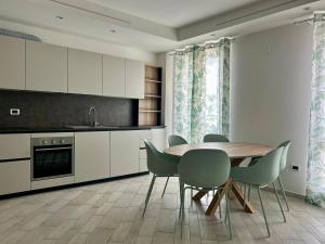 a kitchen with a wooden table and chairs at Appartamento Borgomarina in Cervia +14 photos
