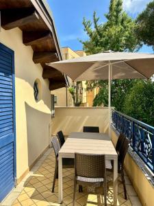 a table and chairs with an umbrella on a balcony at Appartamento Borgomarina in Cervia