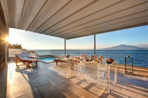 a patio with a table and chairs and the ocean at Villa Tramontana Stunning Waterfront Villa in Vico Equense