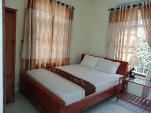 1 dormitorio con 1 cama con cortinas y ventana en Quy Phuong - Homestay, en Tân Hiệp