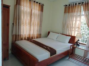 a bedroom with a bed with curtains and a window at Quy Phuong - Homestay in Tân Hiệp