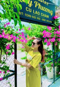 een vrouw die voor een hek staat met bloemen bij Quy Phuong - Homestay in Tân Hiệp