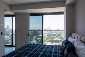 a bedroom with a bed and a large window at Mexication Penthouse: Urban Retreat Col. American in Guadalajara