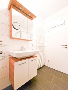 ein weißes Badezimmer mit einem Waschbecken und einem Spiegel in der Unterkunft De Möhlenkieker 3 in Greetsiel