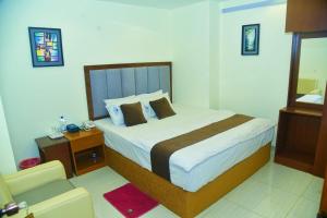 a bedroom with a large bed and a chair at Hotel Crown City in Chittagong