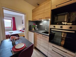 a kitchen with a table and a kitchen with a microwave at Gîte Myosotis, studio 2 personnes, avec salle de jeux et SPA dans la résidence in Ventron