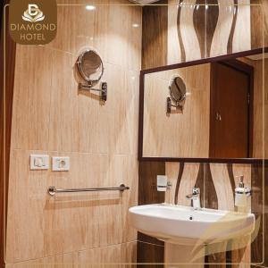 a bathroom with a sink and a mirror at Diamond Land Hotel in Madinat Al Ashir min Ramadan