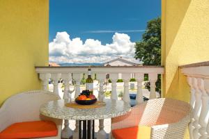 a table with a bowl of fruit and wine bottles on a balcony at Vila Panorama in Malinska