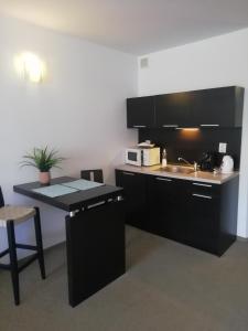 una cocina con armarios negros, fregadero y mesa en Atlantis Resort D111 апартамент, en Burgas