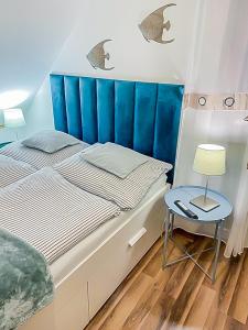 a bedroom with a bed with a blue headboard and a table at Haus Nathalie in Trzęsacz
