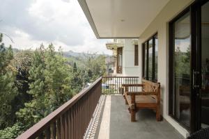 a balcony with a wooden bench and a view at Pinus Villa 5 bedroom with a private pool in Bandung