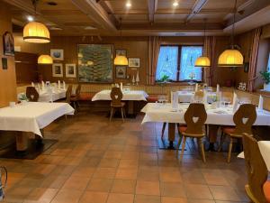 une salle à manger avec des tables et des chaises blanches dans l'établissement Gasthof Hotel Engel, à Simonswald