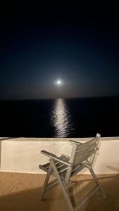 una silla blanca sentada en la playa frente al océano en Sifnos "Sofia apartments" sea view, en Faros