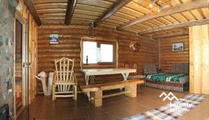 eine Blockhütte mit einem Tisch, einer Bank und einem Bett in der Unterkunft Private House Затишок in Schdenijewo