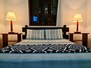 a bedroom with a bed with two lamps on both sides at Pousada Suites Nova Mar Ilhabela in Ilhabela +8 photos