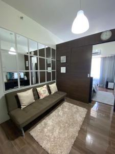 ein Wohnzimmer mit einem Sofa und einer Uhr an der Wand in der Unterkunft Air Residences 1-Bedroom condo in Makati in Manila