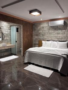 1 dormitorio con 1 cama grande y pared de piedra en Pousada Raio de Luz, en Pirenópolis