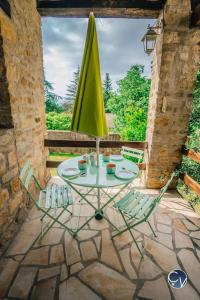 a table with two chairs and a green umbrella at ☆MAISON PROVENCALE☆3chambres☆Idéal famille in Saint-Marcel-de-Carreiret