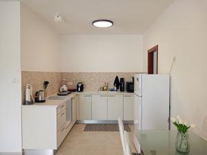 a kitchen with white cabinets and a refrigerator at Agamim Park Residence in Ashqelon