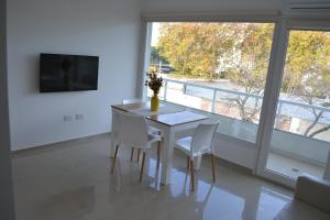 a white table and chairs in a room with a window at Calmo Dooneo Appart La Plata - Departamentos con COCHERA in La Plata