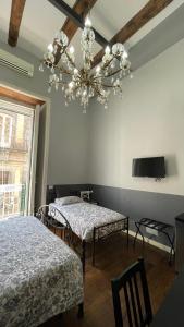 1 dormitorio con 2 camas y lámpara de araña en Anima Partenopea, en Nápoles