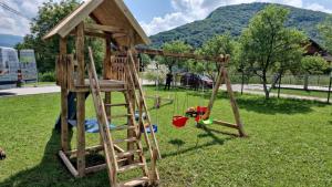 a wooden playground with a play structure in the grass at Villa Tasnim in Dobrenica