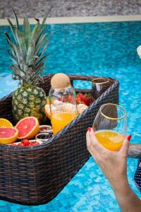 una mujer sosteniendo una cesta de frutas y bebidas en una piscina en Harmonia Bungalows & Pool, en Sveti Stefan