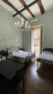 a bedroom with two beds and a table and a chandelier at Anima Partenopea in Naples