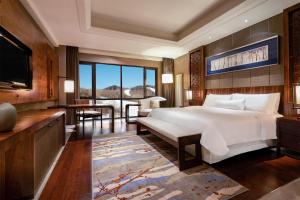 a bedroom with a large bed and a television at The Westin Changbaishan Resort in Fusong