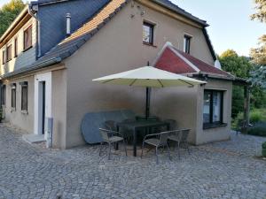 - une table et des chaises avec un parasol en face d'une maison dans l'établissement Ferienwohnung Max, à Schirgiswalde