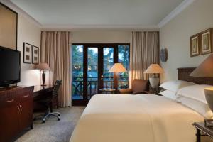 um quarto de hotel com uma cama, uma secretária e uma televisão em Sheraton Lampung Hotel em Bandar Lampung