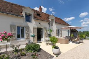 a house with a patio and an umbrella at Le Clos des Roses in Meusnes