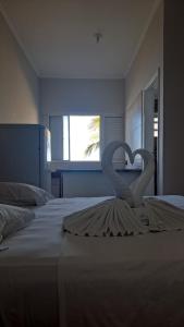 Dos cisnes forman un corazón en una cama en Hotel Pousada Miami, en Itanhaém