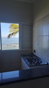 a kitchen with a stove and a view of the ocean at Hotel Pousada Miami in Itanhaém