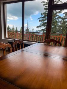 a large wooden table with chairs and a large window at 2 bedroom "Pine Hug" apartment in Borovets