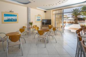 a restaurant with tables and chairs and a pool at Cosmi Apts Gouves by Estia in Gouves