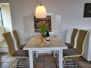 - une table à manger blanche avec des verres à vin et des fleurs dans l'établissement Ferienwohnung 58 im Haus Villa Anna, à Sankt Peter-Ording