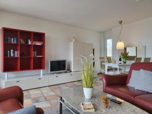 - un salon avec un canapé rouge et une télévision dans l'établissement Ferienwohnung 58 im Haus Villa Anna, à Sankt Peter-Ording