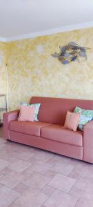 um sofá rosa com almofadas sentadas num quarto em Casa Agnese em Marina di Camerota