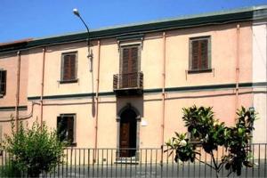 un gran edificio blanco con una valla delante en Bed & Breakfast Casa Pisanu, en Narbolia