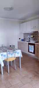 uma cozinha com uma mesa e uma cozinha com armários brancos em Casa Agnese em Marina di Camerota