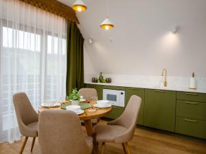 a kitchen with green cabinets and a table with chairs at Apartamenty Górski Prestige in Białka Tatrzanska +88 photos