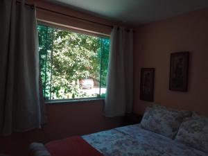 a bedroom with a bed and a large window at B&B Caminho da Floresta in Miguel Pereira